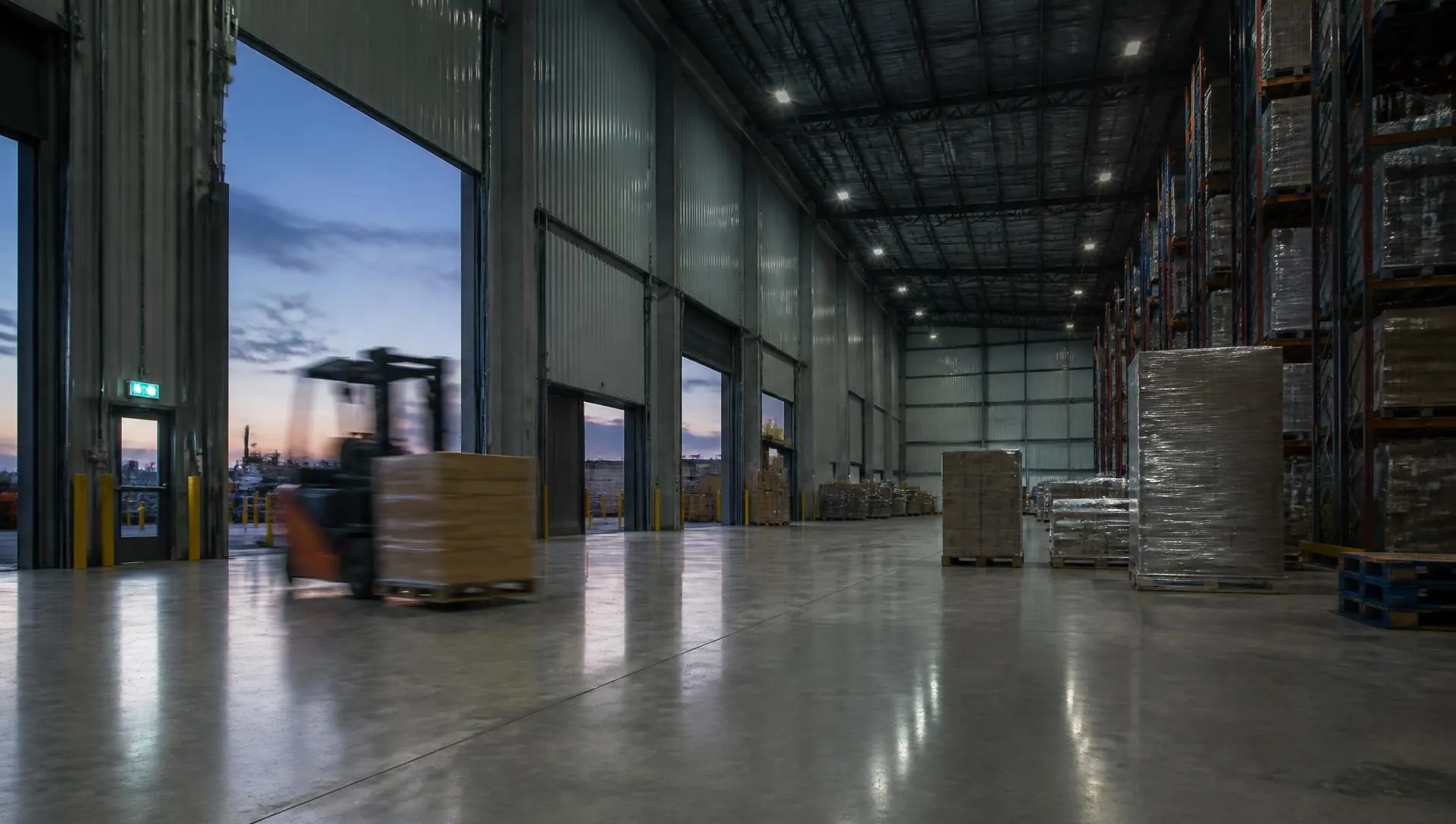 Distribution warehouse interior at dusk with racking and a forklift moving pallets